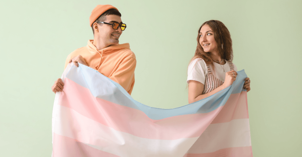 Grupo de pessoas felizes celebrando a Visibilidade Trans com bandeiras.