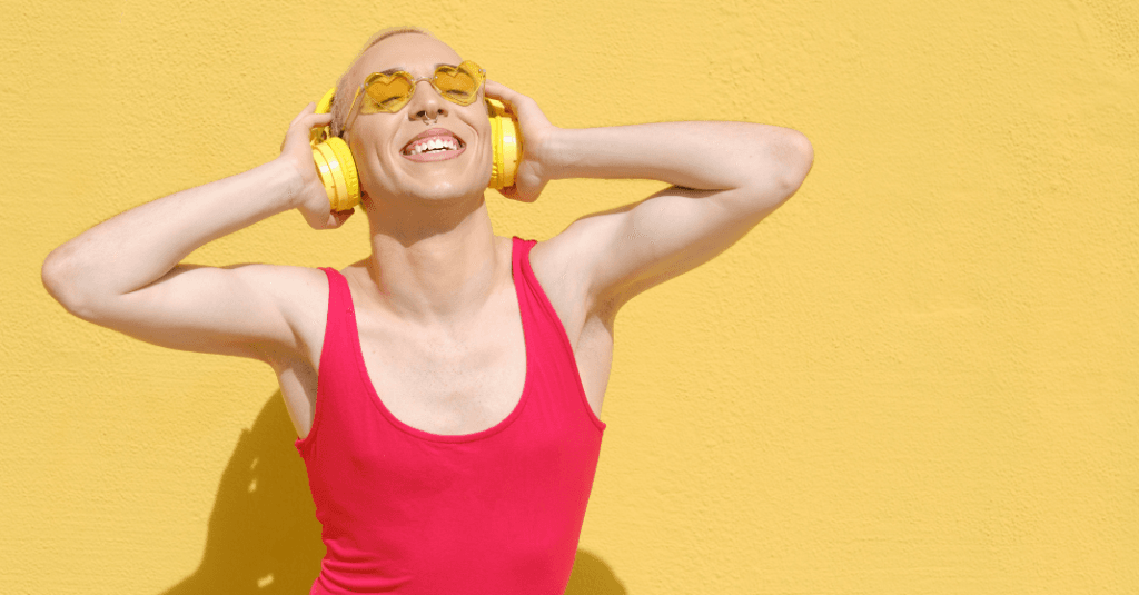 Existir fora do binário: Uma pessoa jovem adulta, usando fones de ouvido com cancelamento de ruído e roupas confortáveis (estilo sem gênero), com um semblante de felicidade, em um ambiente seguro.