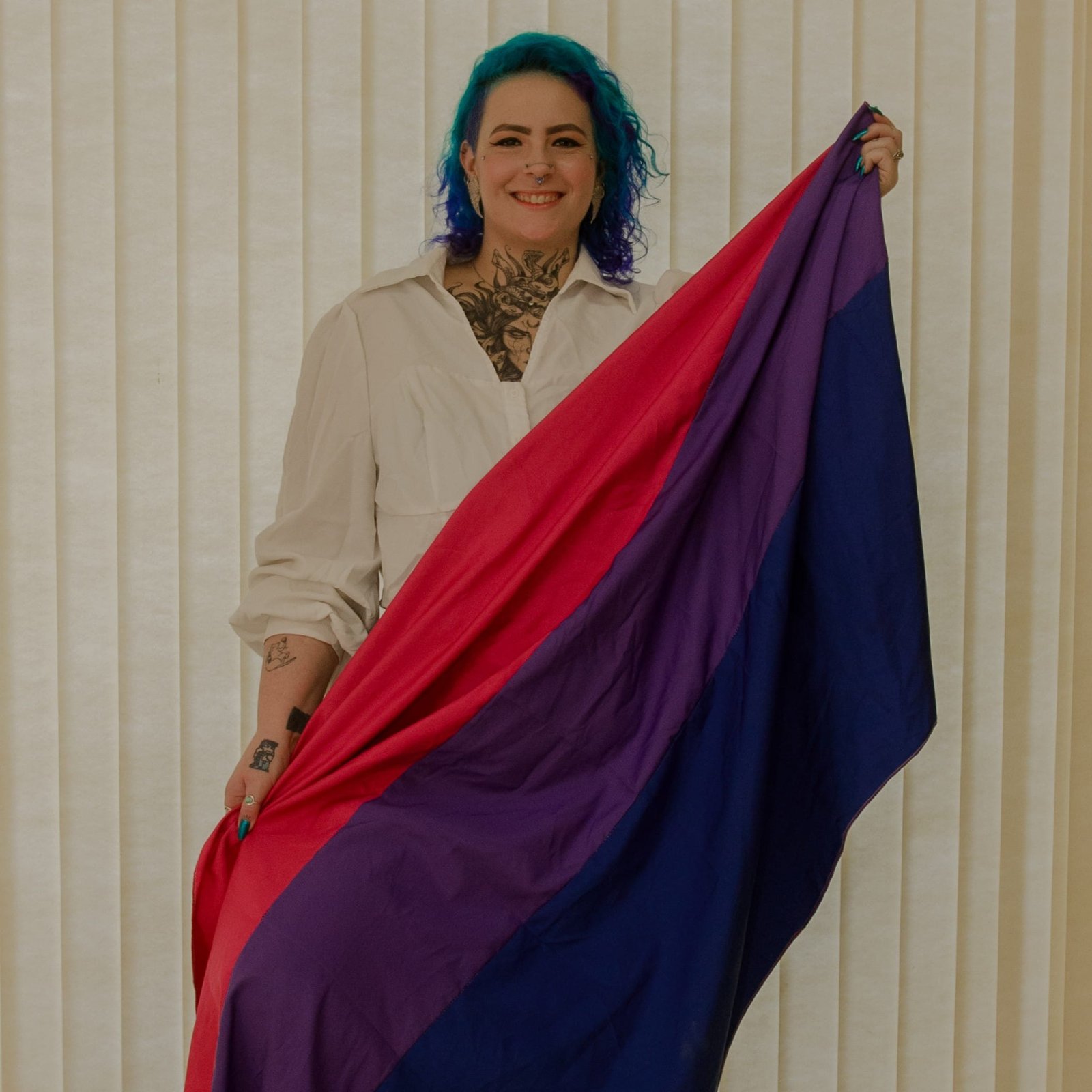 Foto profissional de uma pessoa neurodivergente e bissexual, segurando a bandeira do orgulho bissexual.